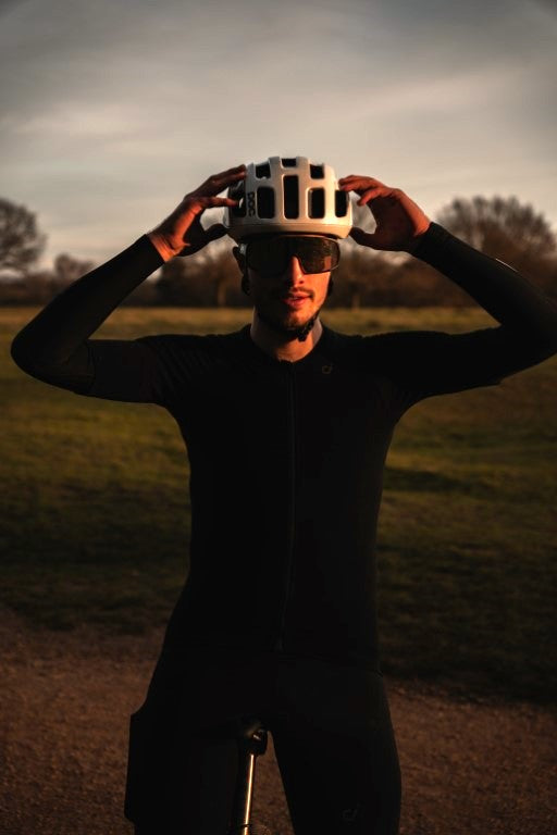 Man astride a titanium bike in the countryside with white cycling helmet and dark glasses