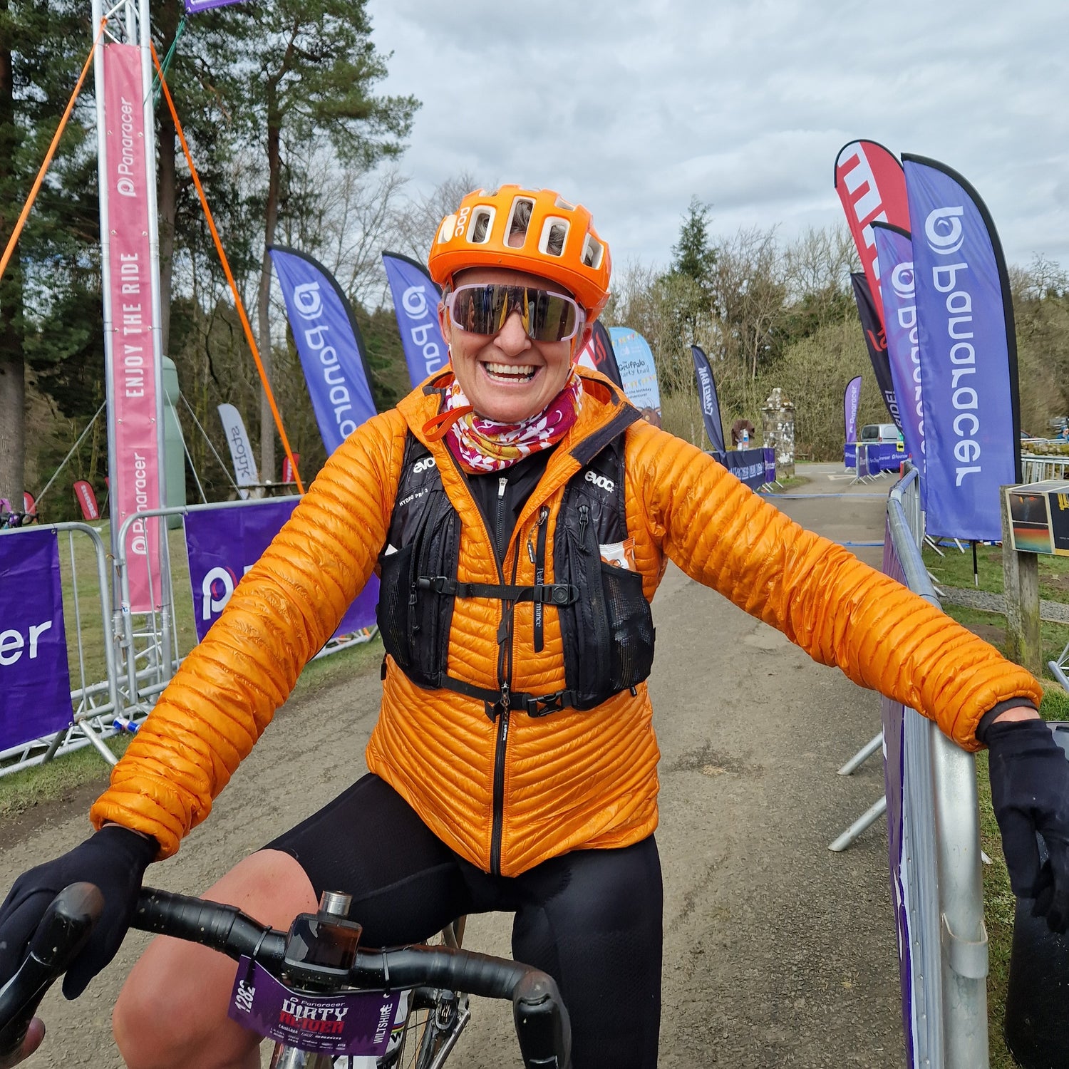 Smiling Cyclist with orange POC helmet and orange jacket at the finish line of a race.