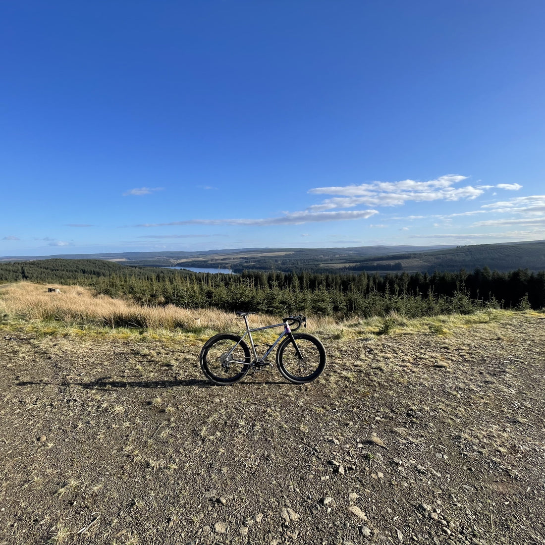 A bike in a deserted landscape on gravel path with blue sky and lake in the distance.