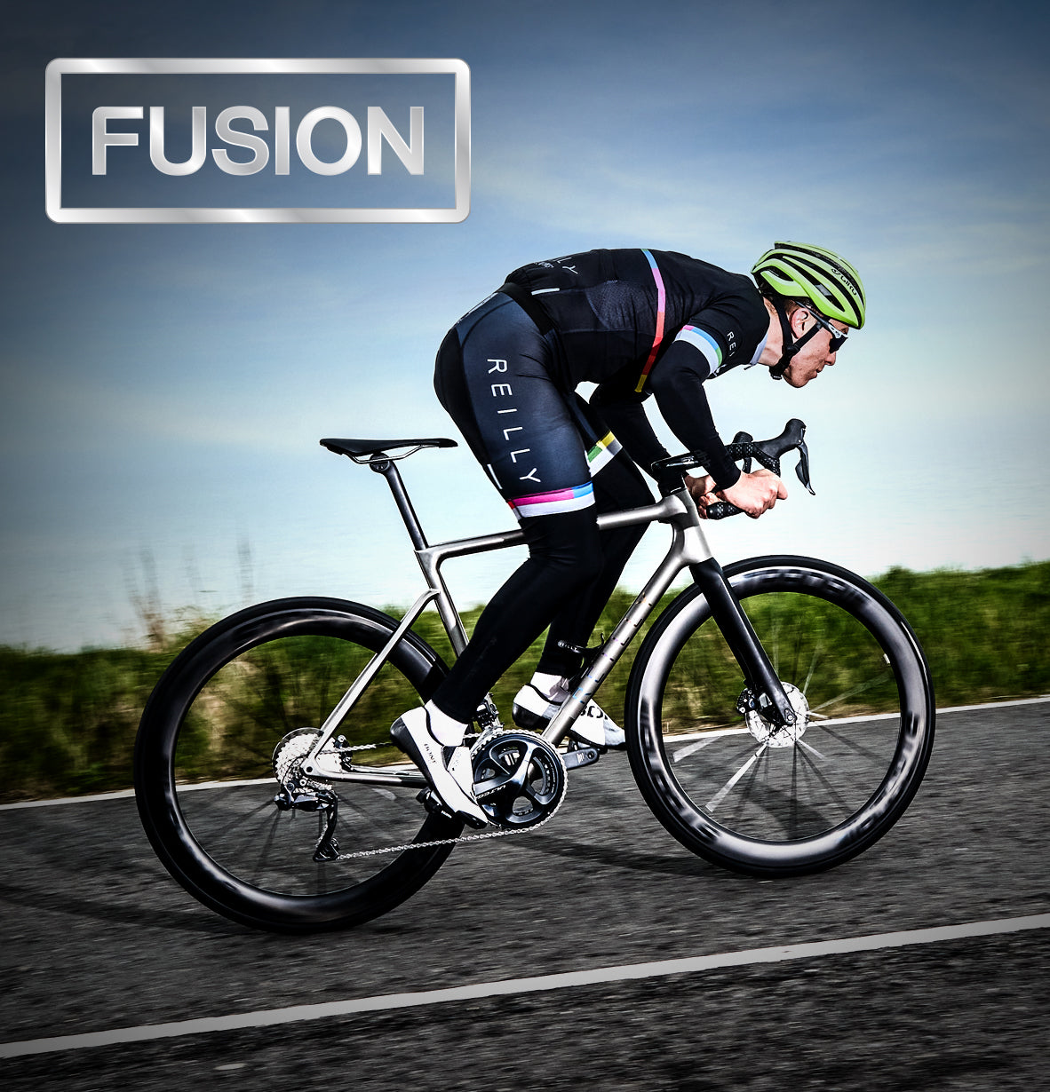 Side view of male cyclist going uphill on a titanium road bike. FUSION is written top left.