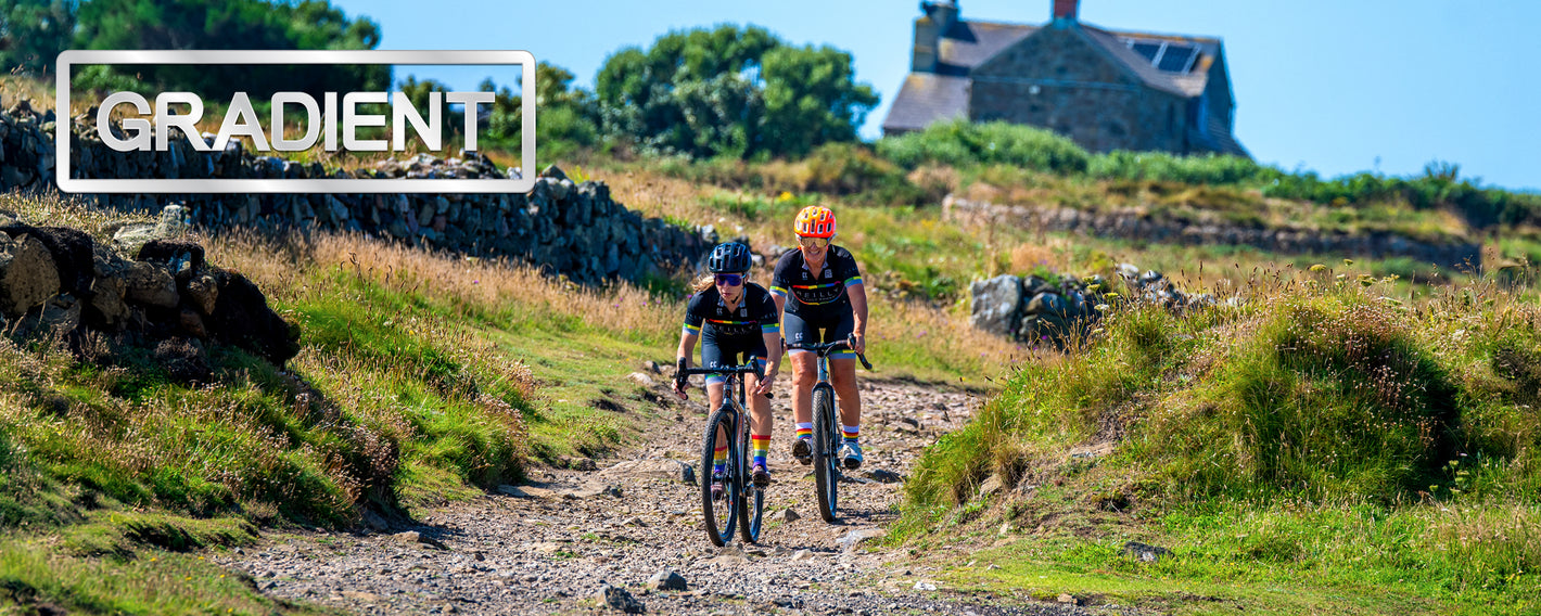 Two women cycle along a gravel path. 