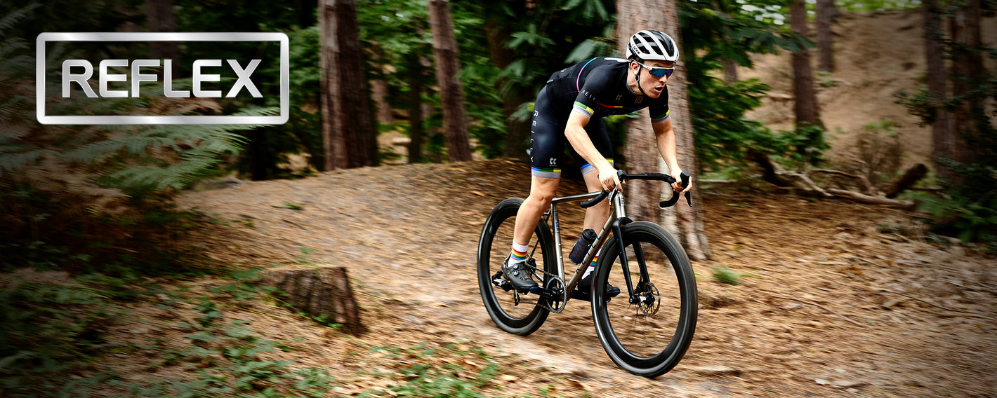 Man on gravel race bike going downhill in forest.  Word REFLEX top left.