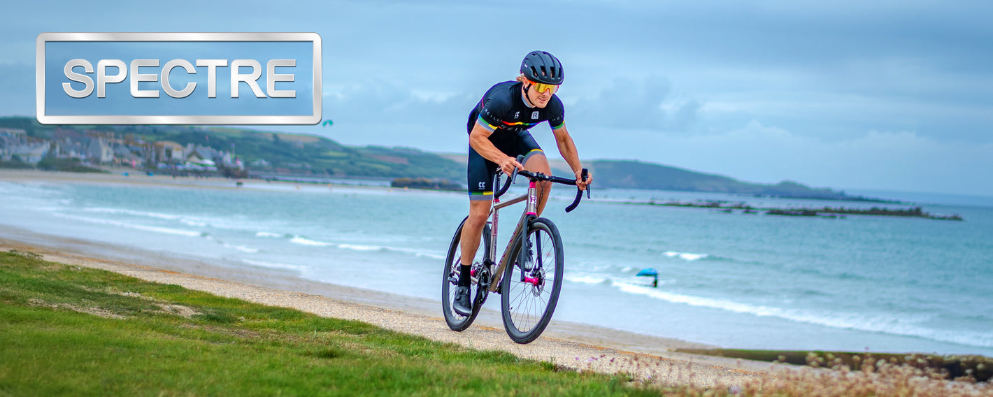 A male cyclist cycles along a path next to the sea.