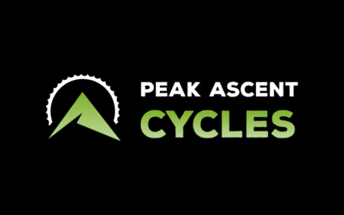 Green Peak with a cog shaped sun and words Peak Ascent Cycles