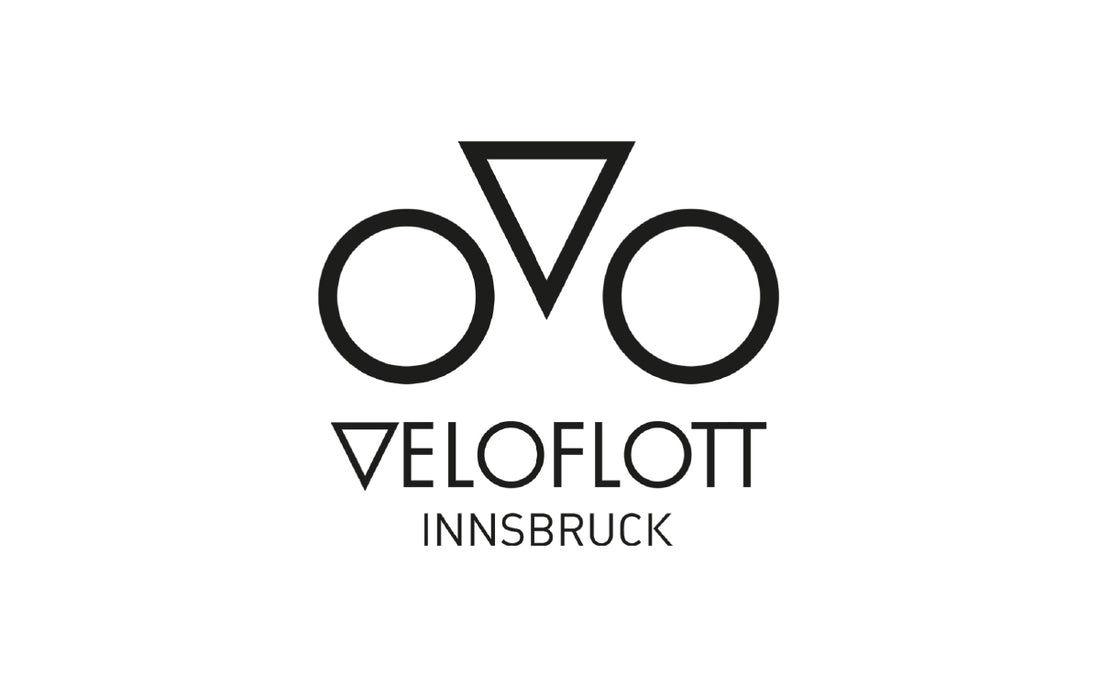A triangle with two wheels positioned to look like a bike plus the wording VeloFlott 