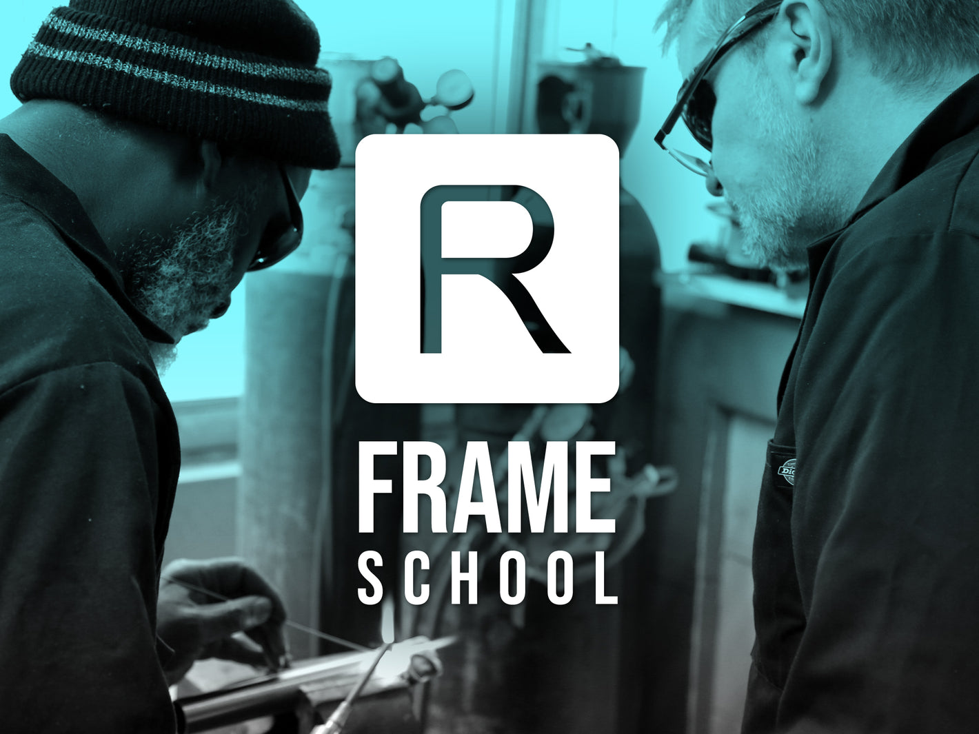 Two men work on a steel bike frame with Reilly logo in foreground with overall blue titnt. 